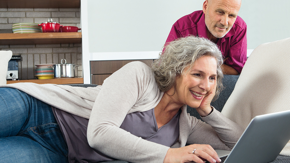 oudere vrouw speelt interactief spel voor handhygiëne op laptop terwijl haar man toekijkt